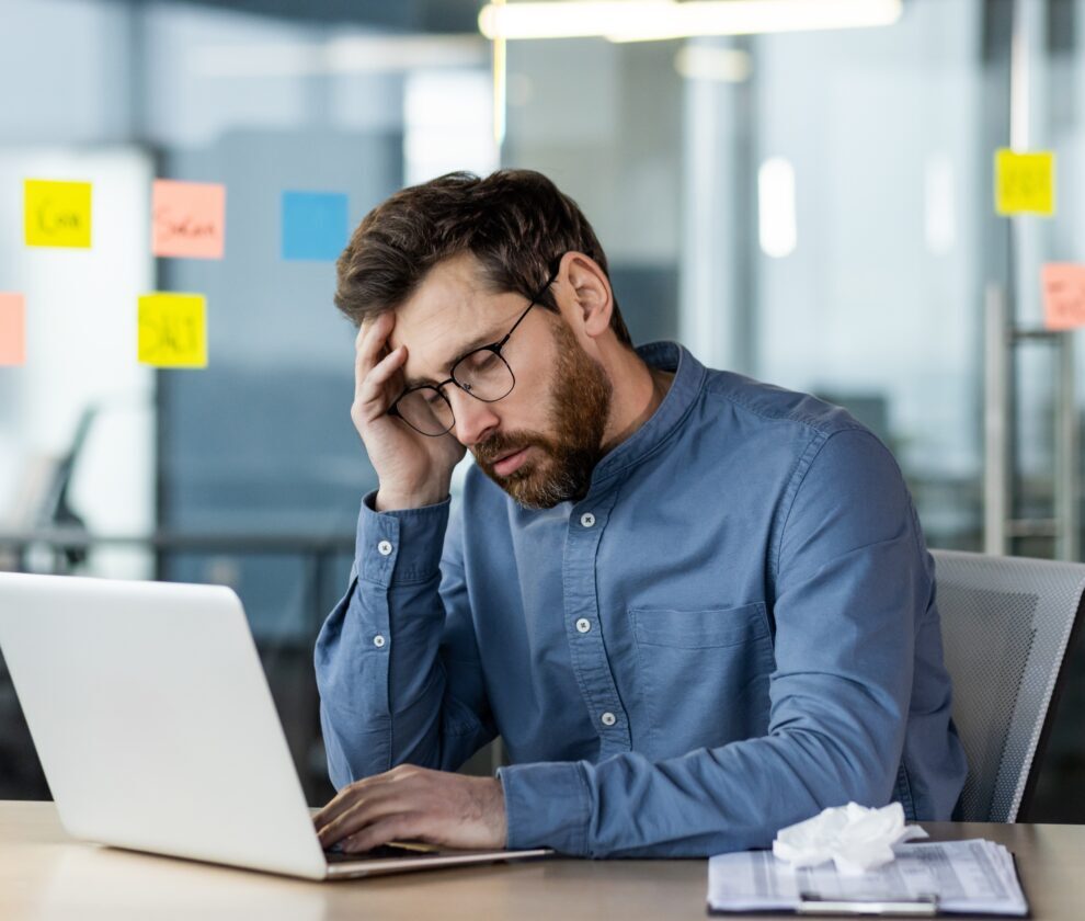 Stressed,Office,Worker,Sitting,At,Desk,With,Laptop,Feeling,Burnout.